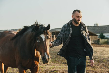 Foto de Un joven agricultor trabaja con caballos en la granja. - Imagen libre de derechos