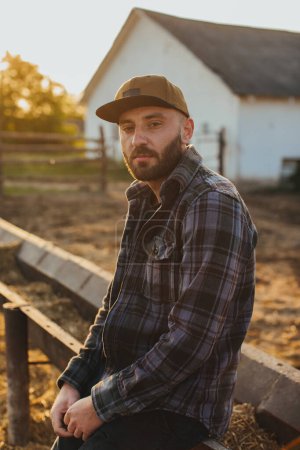 Téléchargez les photos : Portrait d'un beau jeune homme coiffé près de la clôture d'un ranch rural. - en image libre de droit