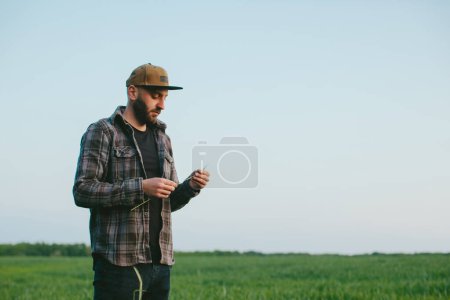 Foto de Un granjero en un campo de trigo al atardecer. Un agrónomo inspecciona un campo de trigo. El concepto de cultivar un nuevo cultivo. - Imagen libre de derechos