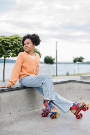 Téléchargez les photos : Mignon jeune afro-américaine fille sur patins à roulettes en plein air. - en image libre de droit