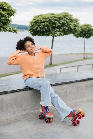Téléchargez les photos : Mignon jeune afro-américaine fille sur patins à roulettes en plein air. - en image libre de droit