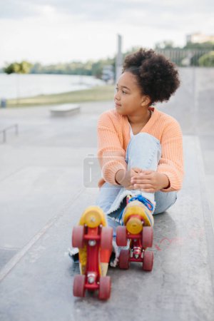 Foto de Linda chica adolescente afroamericana en patines vintage en rampa en el parque de skate en la playa. - Imagen libre de derechos