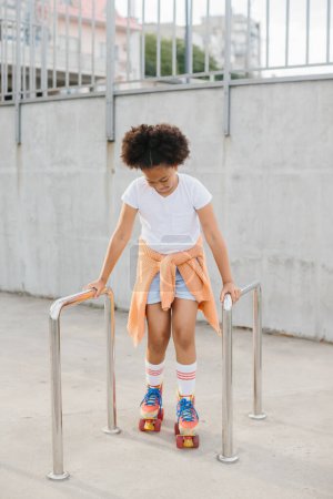 Photo for African-American young girl in roller skates having fun outdoors. - Royalty Free Image