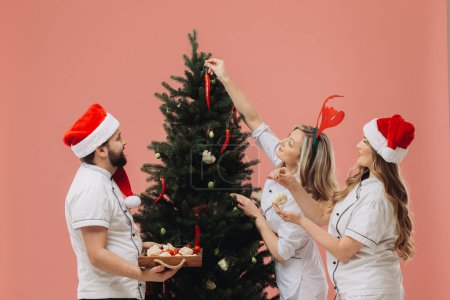 Foto de El concepto de la cocina y las vacaciones de Navidad. Un grupo de cocineros decora un árbol de Navidad con verduras frescas. - Imagen libre de derechos