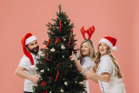 Téléchargez les photos : Le concept de cuisine et vacances de Noël. Un groupe de cuisiniers décore un arbre de Noël avec des légumes frais. - en image libre de droit