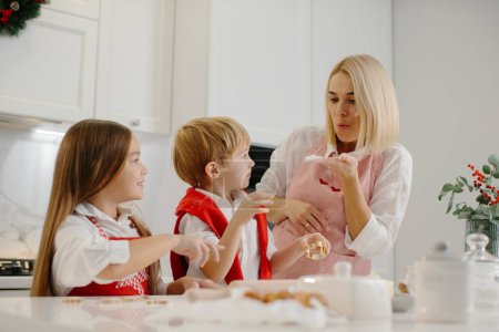 Foto de Madre feliz con los niños cortando diferentes formas de galletas en la cocina. Madre con hija e hijo están haciendo galletas de Navidad en casa y divertirse. - Imagen libre de derechos