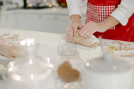 Foto de Primer plano de las manos de la niña amasando masa en la mesa de la cocina. - Imagen libre de derechos