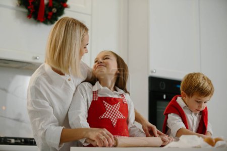 Foto de Navidad, madre e hijos están haciendo galletas en la cocina. Madre enseña a los niños a hornear galletas. - Imagen libre de derechos