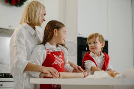 Photo for Christmas, mother and children are making cookies in the kitchen. Mother teaches children to bake cookies. - Royalty Free Image