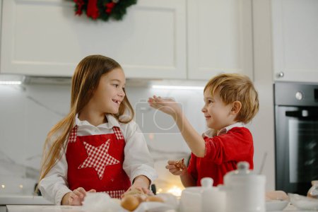 Foto de Los niños se divierten en la cocina mientras hacen galletas de Navidad. - Imagen libre de derechos