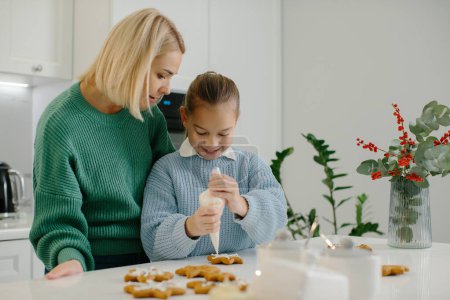 Photo for Mother and daughter prepare Christmas cookies and decorate them with icing for a merry Christmas and happy holiday - Royalty Free Image
