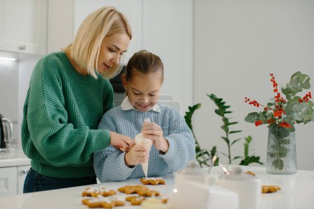 Foto de Madre e hija preparan galletas de Navidad y las decoran con glaseado para una feliz Navidad y unas felices fiestas - Imagen libre de derechos