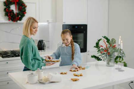 Foto de Madre e hija decoran galletas de Navidad en la cocina. - Imagen libre de derechos