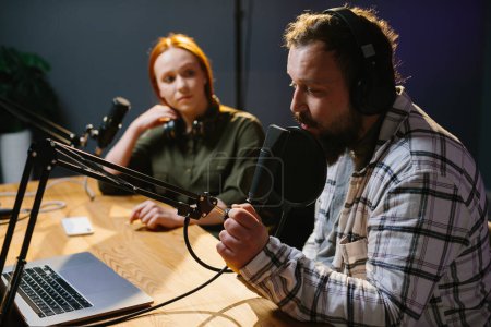 Téléchargez les photos : Deux animateurs de radio dans les écouteurs riant tout en enregistrant podcast en studio ensemblele - en image libre de droit