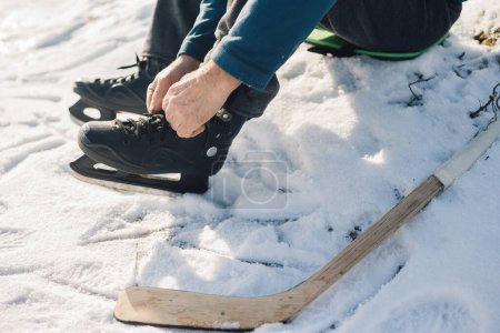 Téléchargez les photos : Ferme là. Un joueur de hockey masculin senior met des patins avant l'entraînement. - en image libre de droit