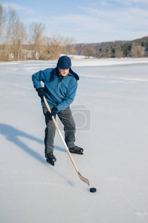 Foto de Hombre mayor jugando hockey en un lago congelado en invierno. - Imagen libre de derechos