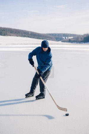 Téléchargez les photos : Homme âgé jouant au hockey sur un lac gelé en hiver. - en image libre de droit