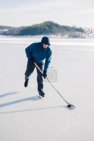 Foto de Hombre mayor jugando hockey en un lago congelado en invierno. - Imagen libre de derechos