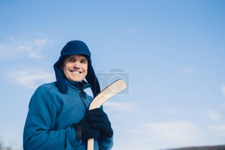 Téléchargez les photos : Portrait d'un homme âgé avec un bâton de hockey sur fond de ciel. - en image libre de droit