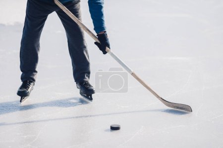Foto de Un anciano practica hockey sobre hielo en un lago congelado en invierno. - Imagen libre de derechos