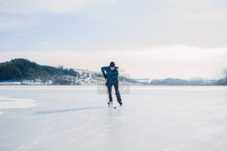 Foto de Un anciano practica el stricking del disco con palos de hockey en un lago congelado en invierno. - Imagen libre de derechos
