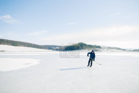 Téléchargez les photos : Homme âgé en patins à glace avec bâton de hockey sur un lac gelé en hiver. Concept hobby des personnes âgées. - en image libre de droit