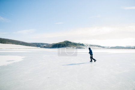 Photo for Senior man on ice skates with hockey stick on frozen lake in winter. Hobby concept of elderly people. - Royalty Free Image