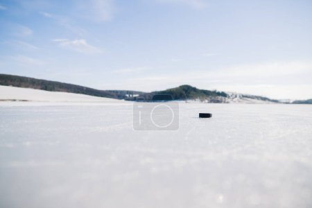 Foto de Hockey puck en un lago congelado en invierno contra el fondo de las montañas. - Imagen libre de derechos
