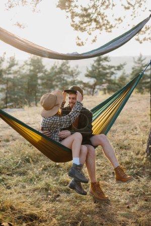 Photo for A couple in love are hugging while lying in a hammock in nature. - Royalty Free Image