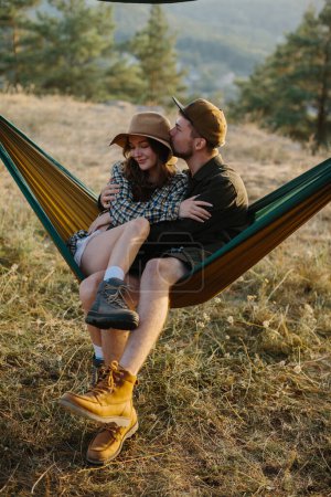 Foto de Una pareja enamorada se abrazan mientras yacen en una hamaca en la naturaleza. - Imagen libre de derechos