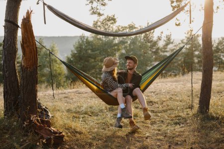 Photo for Happy couple in love enjoying the sunset outdoors while relaxing in a hammock. - Royalty Free Image