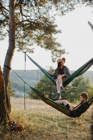 Téléchargez les photos : Un jeune homme et une belle jeune femme se reposent dans des hamacs dans les montagnes. Le concept de détente et d'unité avec la nature. - en image libre de droit