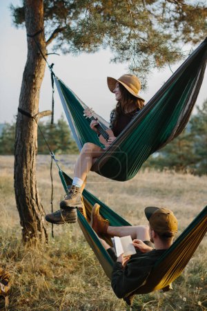 Téléchargez les photos : Du repos esthétique. Une belle jeune fille et son petit ami se détendent dans des hamacs au coucher du soleil. - en image libre de droit