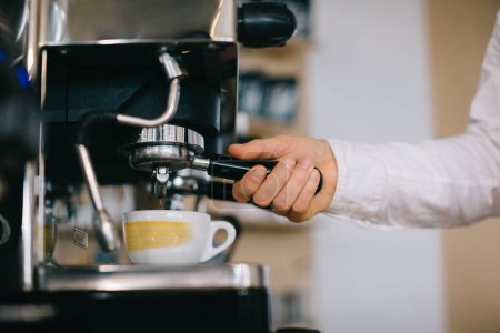 Téléchargez les photos : Un barista prépare le café à l'aide d'une machine à expresso. Gros plan d'un homme qui prépare un café dans un café. - en image libre de droit