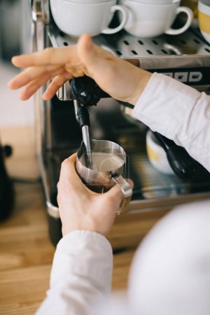 Téléchargez les photos : Un barista prépare le lait pour le cappuccino à l'aide d'une machine à expresso. Gros plan d'un homme qui prépare un café dans un café. - en image libre de droit