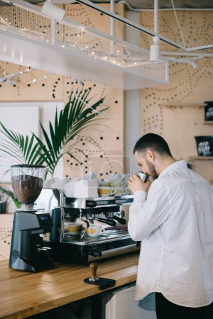 Foto de Un barista cerca de una cafetera espresso prepara un delicioso café. Un joven prepara café en un café. - Imagen libre de derechos