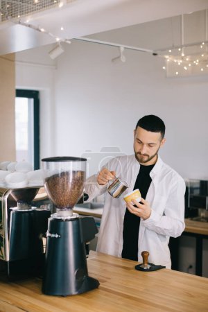 Foto de Un barista cerca de una cafetera espresso prepara un delicioso café. Un joven prepara café en un café. - Imagen libre de derechos