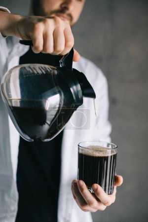 Foto de Barista guapo verter café recién hecho goteo en una taza de vidrio. Preparación de café método alternativo. - Imagen libre de derechos