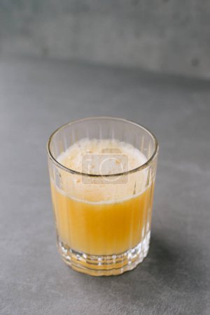 Téléchargez les photos : Gros plan d'un verre de jus d'orange sur un fond de pierre grise. - en image libre de droit