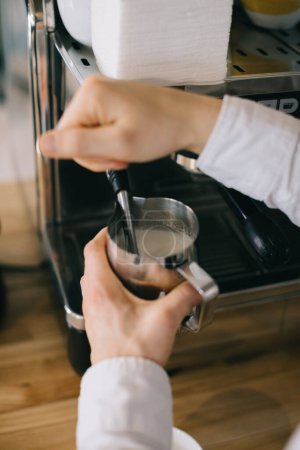 Téléchargez les photos : Un barista prépare le lait pour le cappuccino à l'aide d'une machine à expresso. Gros plan d'un homme qui prépare un café dans un café. - en image libre de droit