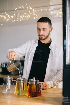 Photo for A young barista man prepares delicious teas in a modern cafe. - Royalty Free Image