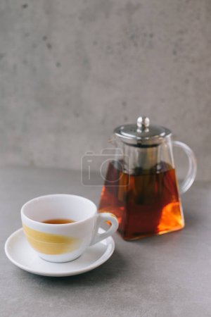 Téléchargez les photos : Théière en verre et tasse avec thé aromatique isolé sur fond gris. - en image libre de droit