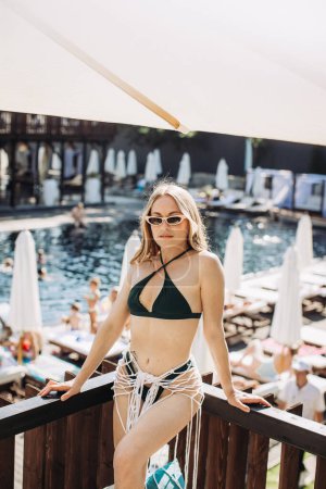 Téléchargez les photos : Une jolie femme blonde en lunettes de soleil et un maillot de bain pose sur le fond de la piscine. - en image libre de droit