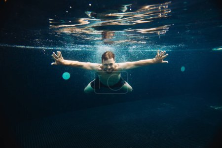 Téléchargez les photos : Un jeune homme nage sous l'eau dans une piscine. Concept vacances d'été. - en image libre de droit