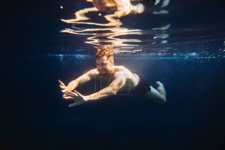 Photo for A young man swims underwater in a pool. Summer vacation concept. - Royalty Free Image