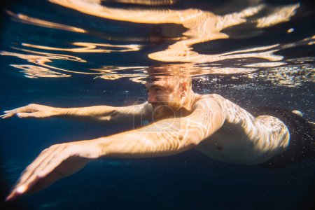 Foto de Un joven guapo nada bajo el agua en una piscina mientras está de vacaciones. - Imagen libre de derechos