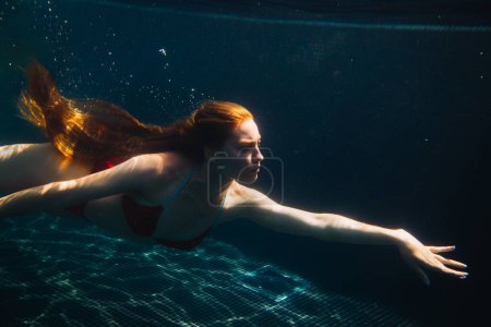 Foto de Joven pelirroja nadando bajo el agua en una caca - Imagen libre de derechos