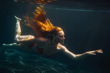 Foto de Joven pelirroja nadando bajo el agua en una caca - Imagen libre de derechos