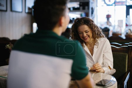 Téléchargez les photos : Un couple s'amuse à discuter autour d'un café le matin dans un café. Une fille rit des blagues de son petit ami. - en image libre de droit