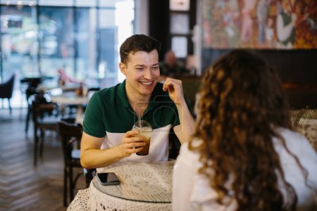 Photo for Happy young couple talking over a cup of coffee in a cafe, man and woman in a coffee shop on a date. - Royalty Free Image